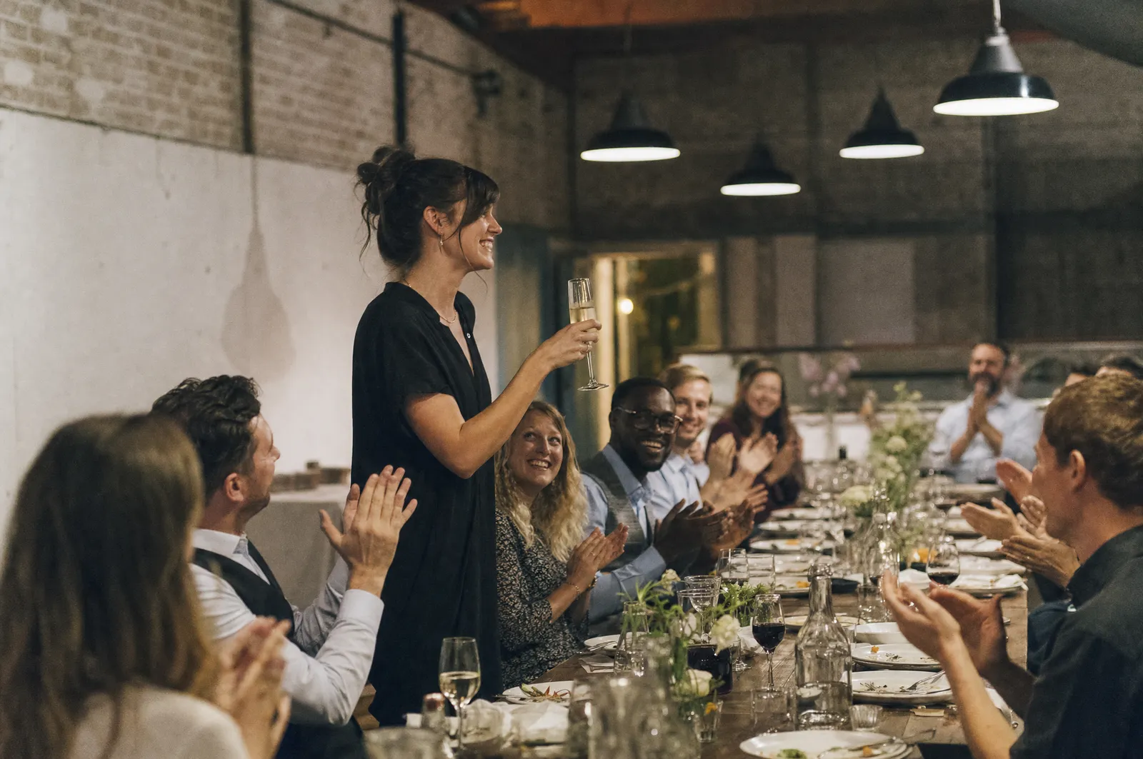 Colleagues applauding a toast at a company celebration dinner