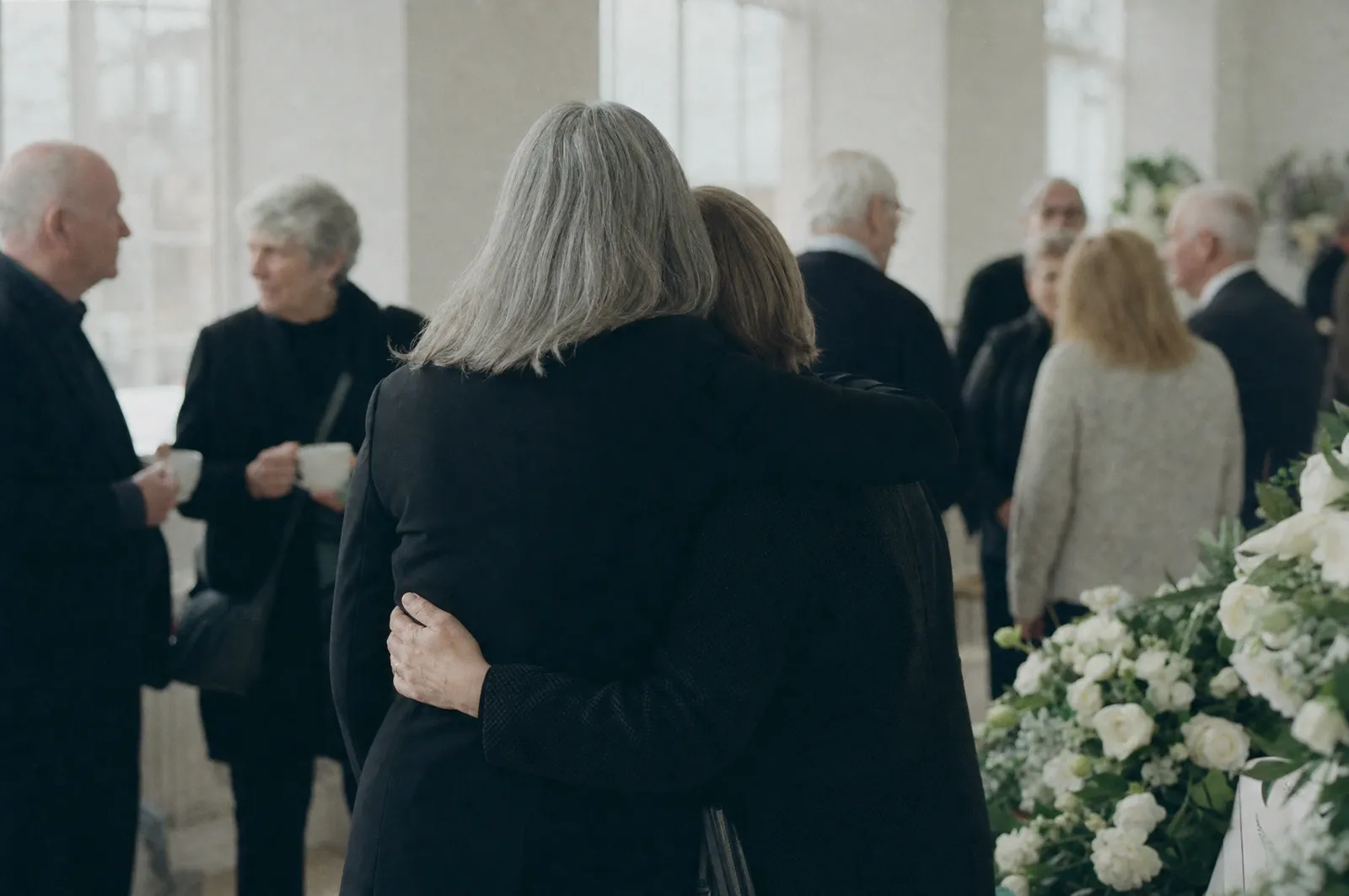 Two people embracing at a gathering after a memorial service